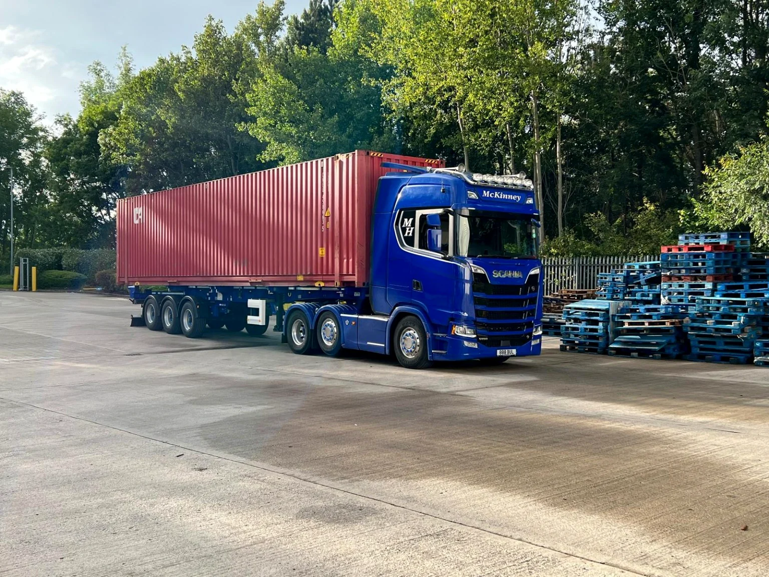 McKinney Haulage tractor unit and skeletal trailer carrying a red shipping container